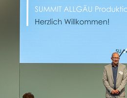 Zwei Herren stehen vor einer Leinwand beim Summit Allgäu Produktion 2025.